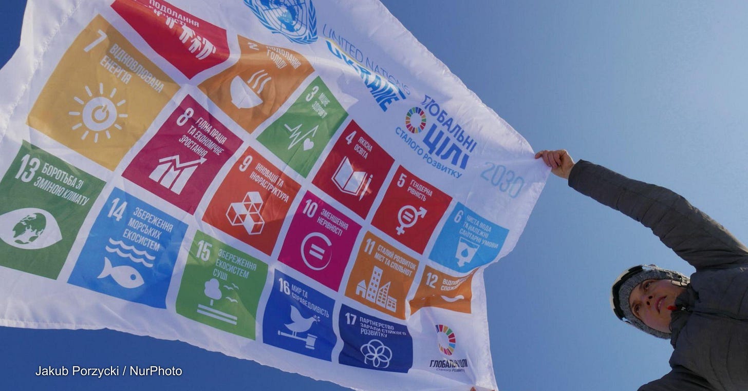 A person unfurls a flag that shows the 17 Sustainable Development Goals. A person unfurls a flag that shows the 17 Sustainable Development Goals.